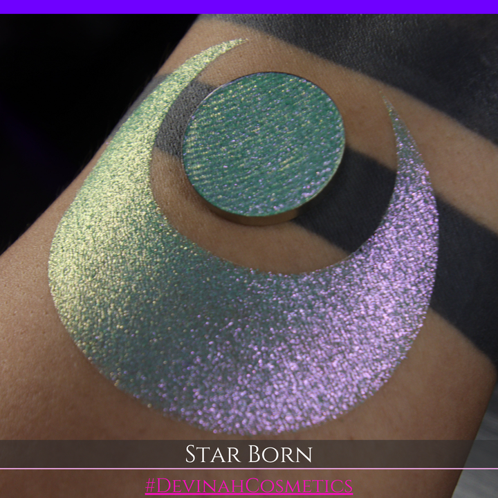 A close-up of a person's skin with a large iridescent crescent moon makeup swatch and a matching circular eyeshadow pan in the center. The text 'STAR BORN' and 'Devinah Cosmetics' appears at the bottom.