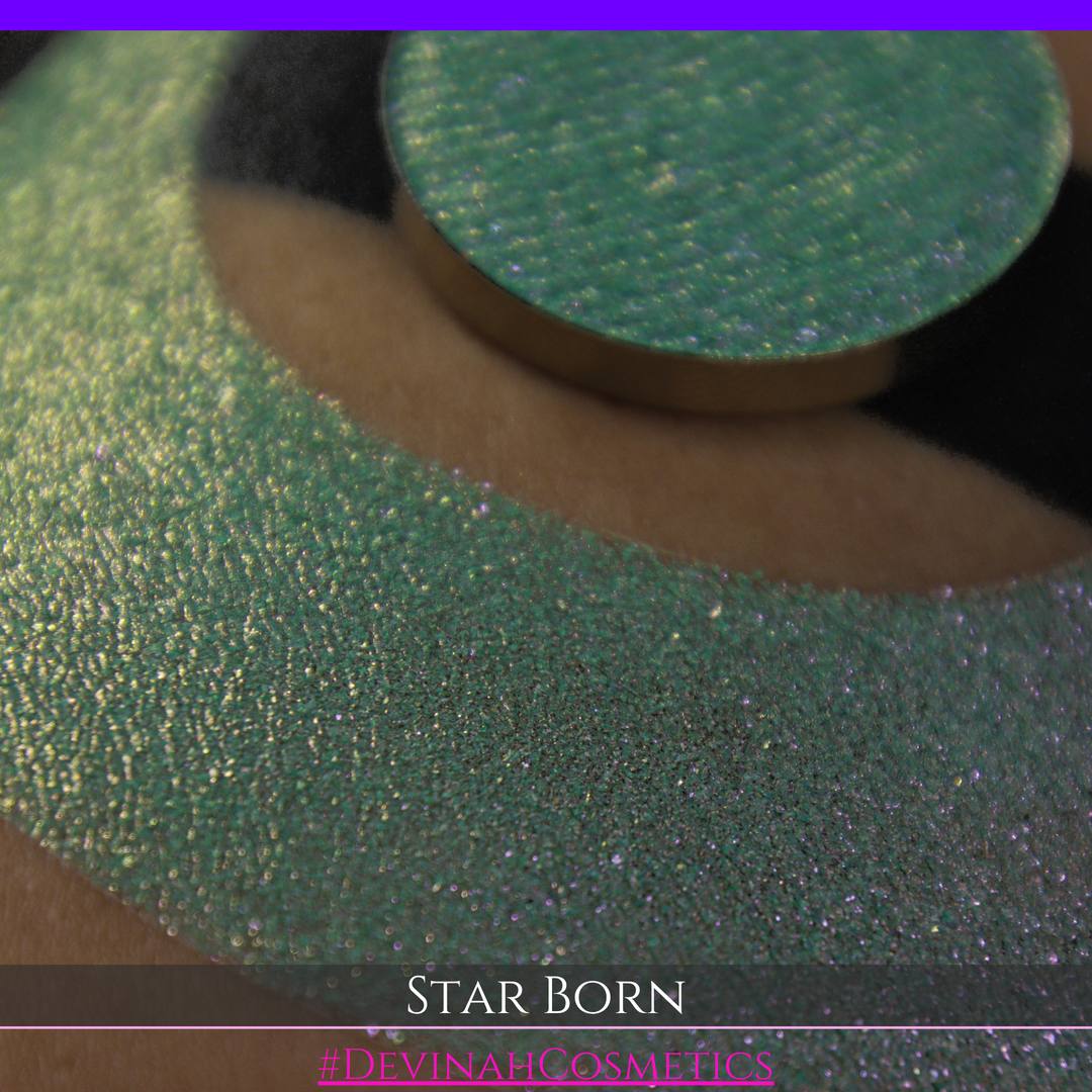 A close-up of a person's skin with a large iridescent crescent moon makeup swatch and a matching circular eyeshadow pan in the center. The text 'STAR BORN' and 'Devinah Cosmetics' appears at the bottom.