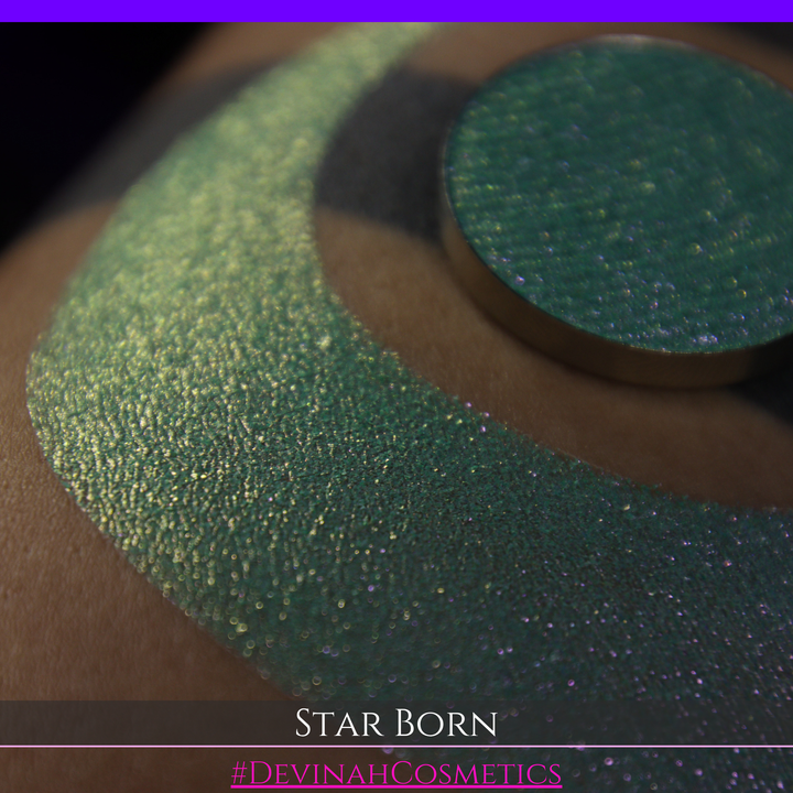 A close-up of a person's skin with a large iridescent crescent moon makeup swatch and a matching circular eyeshadow pan in the center. The text 'STAR BORN' and 'Devinah Cosmetics' appears at the bottom.