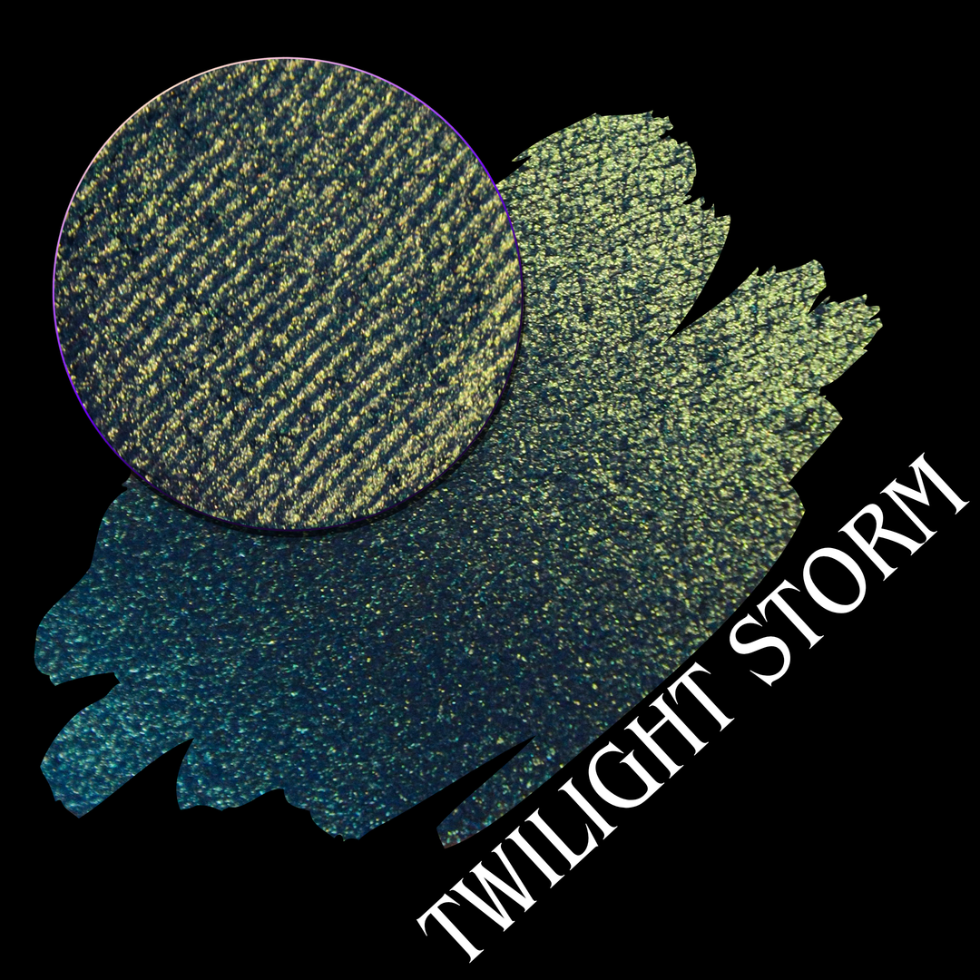 An eyeshadow swatch in a blue-to-yellow gradient with a circular eyeshadow pan, labeled 'TWILIGHT STORM' on a black background handmade by Devinah Cosmetics.