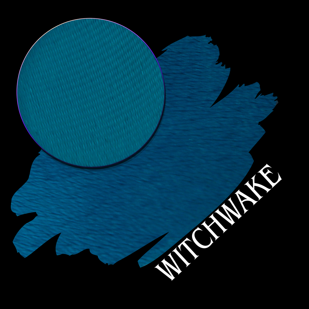 A blue swatch and eyeshadow pan on a black background, with the word 'WITCHWAKE' in white diagonal text.