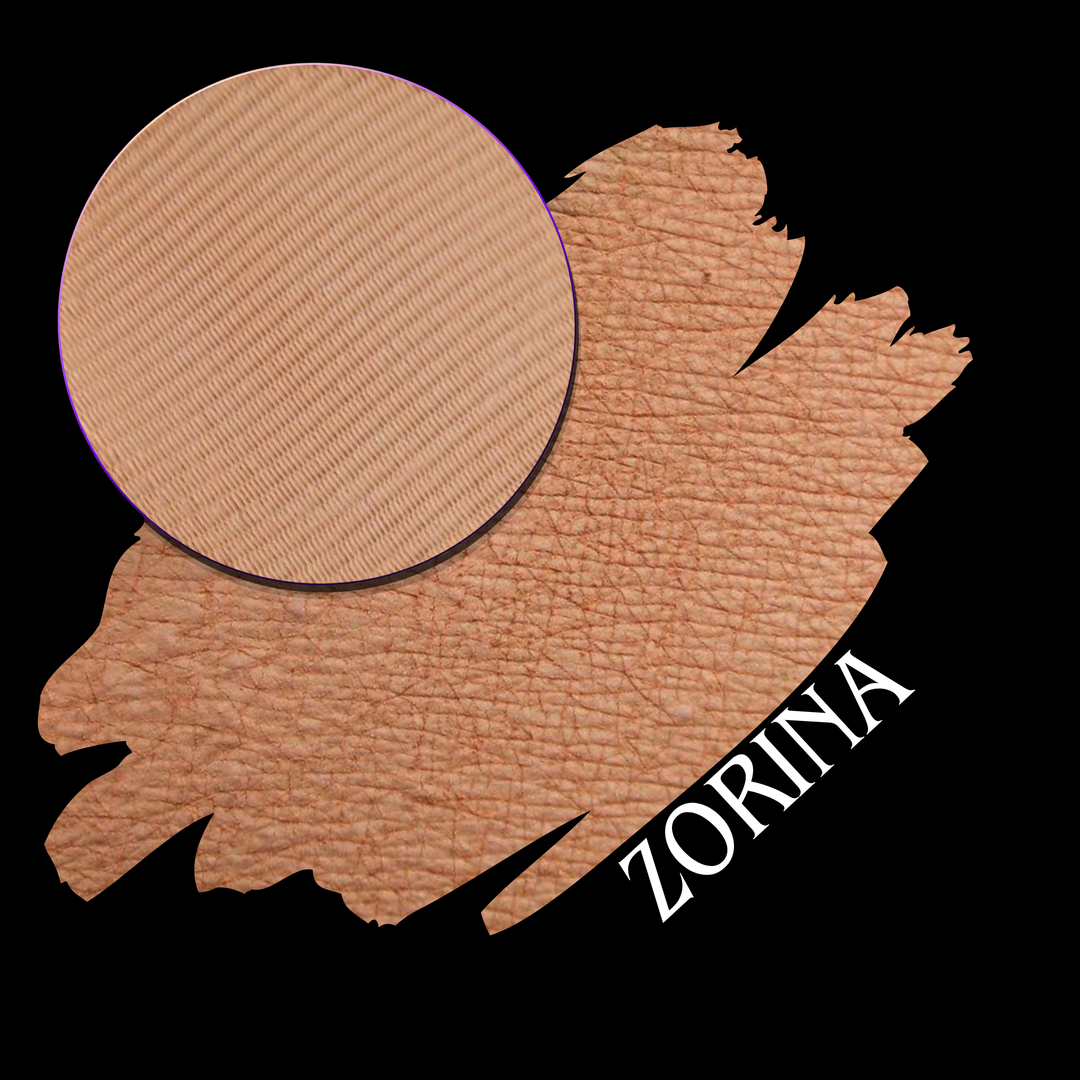 A makeup color swatch showing a circular pressed eyeshadow powder pan over of desaturated peachy shade, with the name 'ZORINA' in white text on a black background.