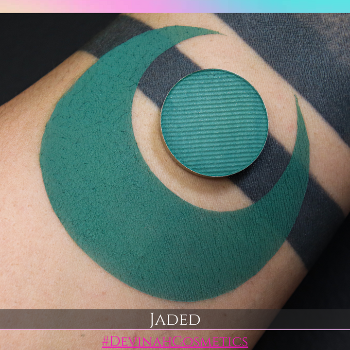 Green eyeshadow makeup pan on a person's arm with 'Jaded' and '#DevinahCosmetics' branding.