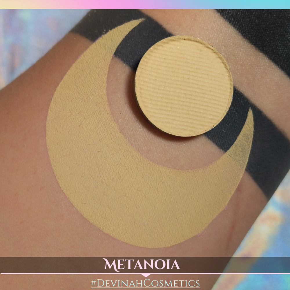Makeup product on skin with 'METANOIA' and '#DEVINAH COSMETICS' branding.