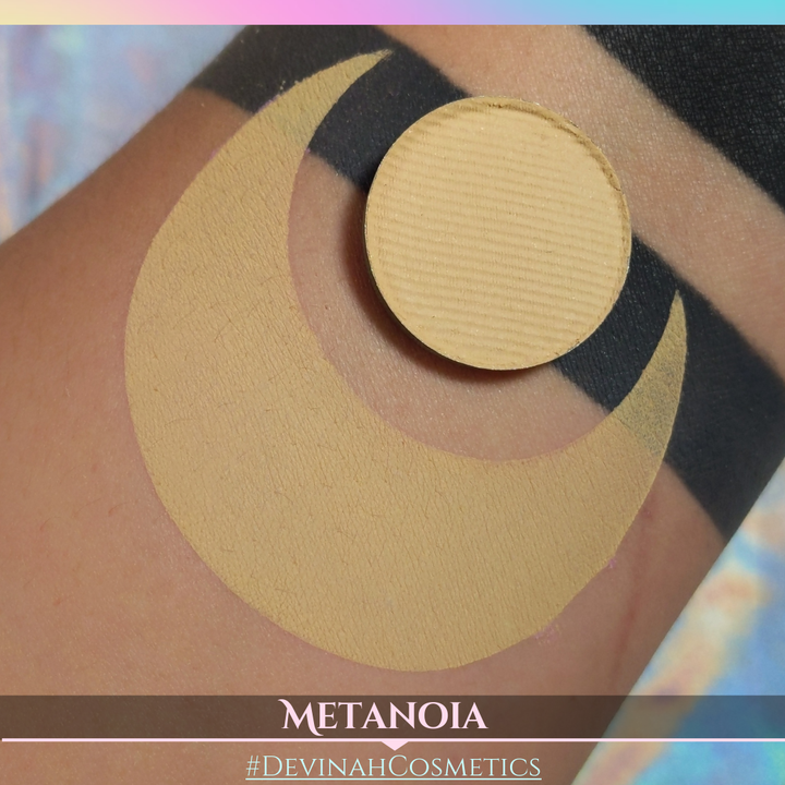 Makeup product on skin with 'METANOIA' and '#DEVINAH COSMETICS' branding.
